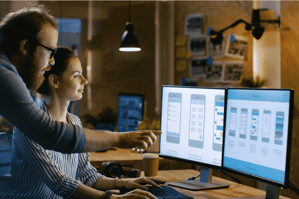 two developers working on an app project on a multi screen computer