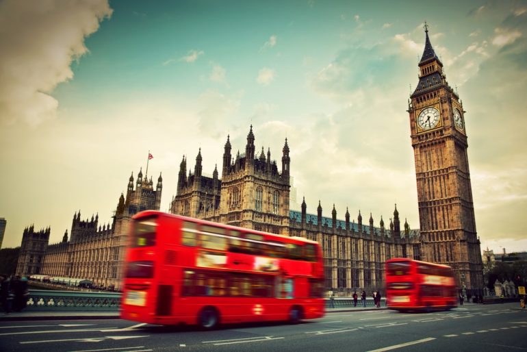 ondon, the UK. Red bus in motion and Big Ben, the Palace of Westminster. The icons of England in vintage, retro style