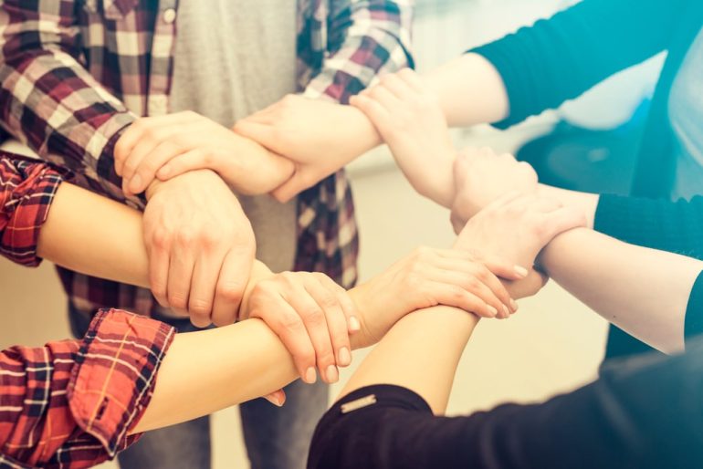 A group of young people hold strong hands. Sign of trust and teamwork.