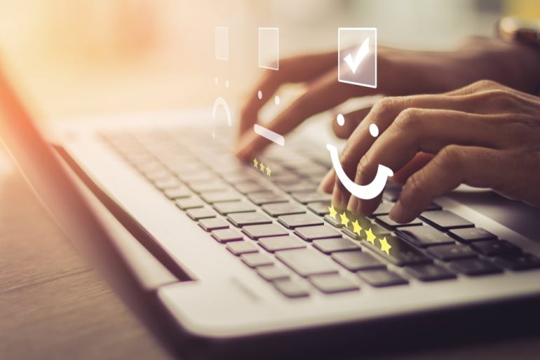 Businesswoman pressing face emoticon on the keyboard laptop / Customer service evaluation concept. - Image