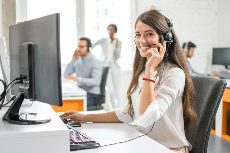 Young friendly operator woman agent with headsets working in a call centre. - Image