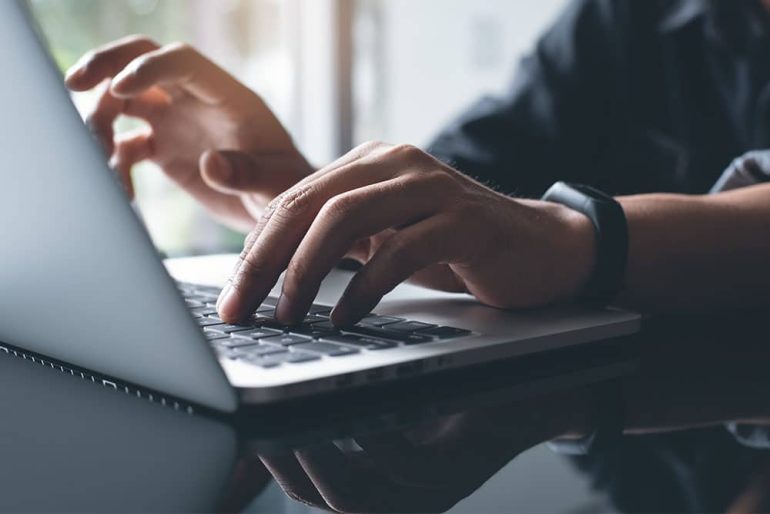 Man on MacBook translating content into another language for a website