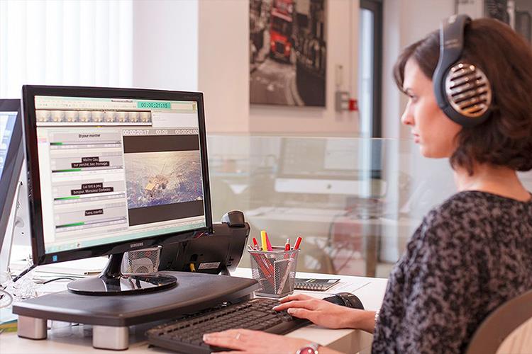 Woman sitting in front of a computer creating subtitles for a video - subtitle